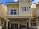 Two-story yellow house with a balcony, garage, and gated entrance