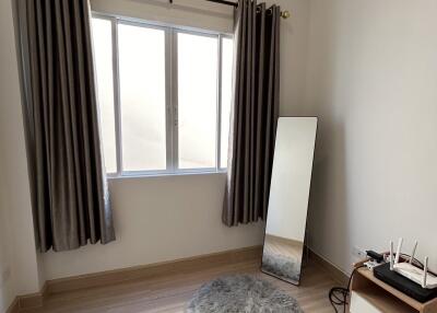 Cozy bedroom with a large window, mirror, and a small rug