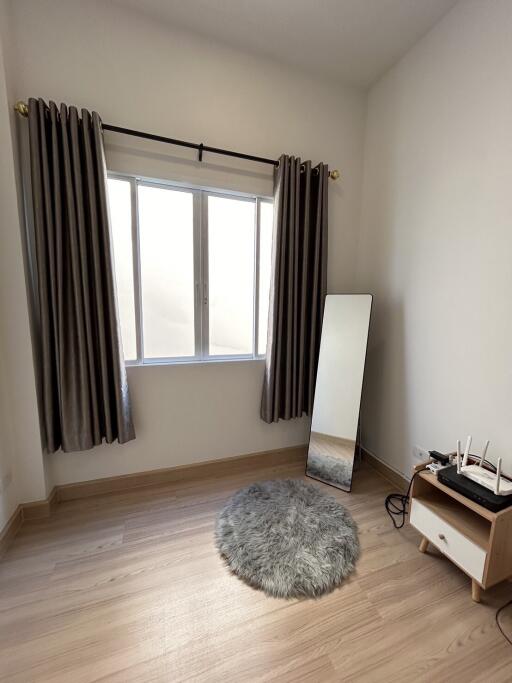 Cozy bedroom with a large window, mirror, and a small rug