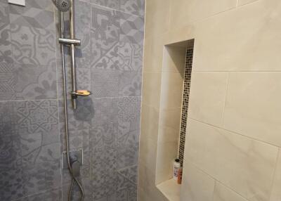 Modern bathroom shower area with patterned and plain tiles