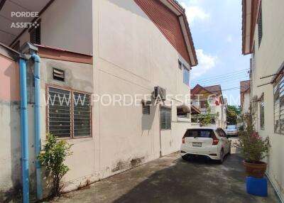 Exterior view of residential apartment building with parking space and potted plants