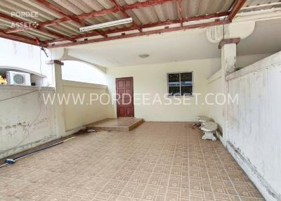 Covered outdoor area with tiled flooring and a red door.