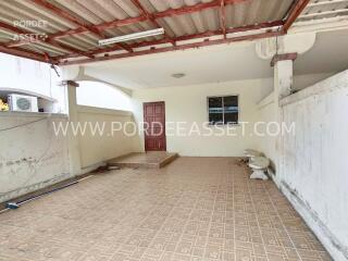 Covered outdoor area with tiled flooring and a red door.