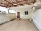 Covered outdoor area with tiled flooring and a red door.