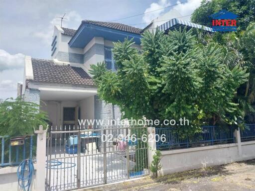 Front exterior view of a two-story residential house with gated entrance and surrounding greenery.