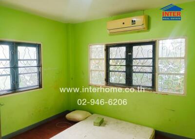 Bright green painted bedroom with multiple windows and an air conditioning unit.