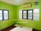 Bright green painted bedroom with multiple windows and an air conditioning unit.