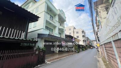 Three-story residential building on a street with other houses