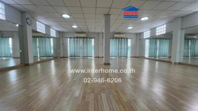 Spacious multi-purpose room with hardwood flooring, wall mirrors, and ceiling lights