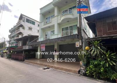 Front view of a multi-level residential building on a street with neighboring houses.