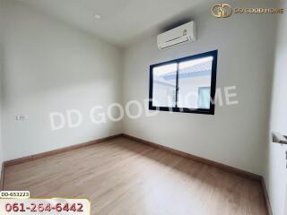 Modern empty bedroom with wooden floor, window, and air conditioner