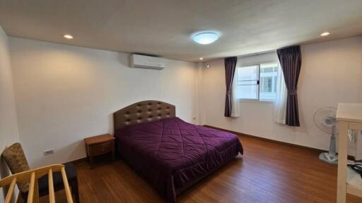 Spacious bedroom with purple bedding and wooden flooring