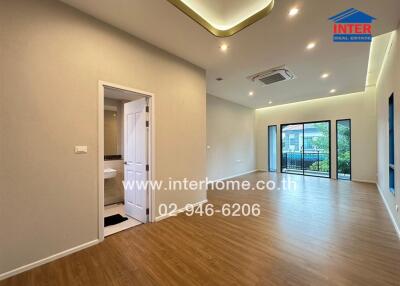 Spacious living room with wooden flooring, modern lighting, and a balcony access