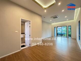 Spacious living room with wooden flooring, modern lighting, and a balcony access