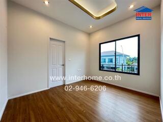 Spacious bedroom with wooden floor and large window