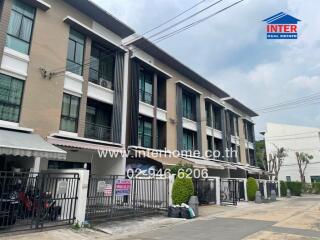 Three-story residential building with balconies and gated entrance