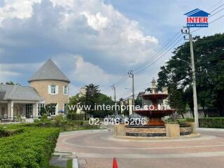 A scenic view of a residential area featuring a pathway, green landscaping, and a large central fountain.