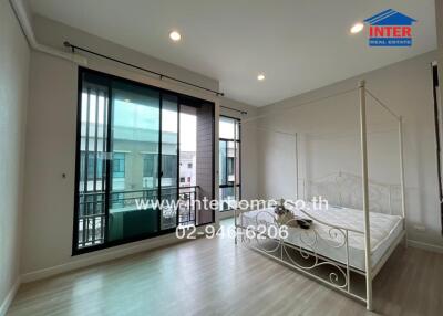 Bright bedroom with a large window and a white bed frame.