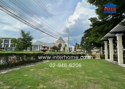 Spacious green yard in a residential area with a fountain and surrounding houses