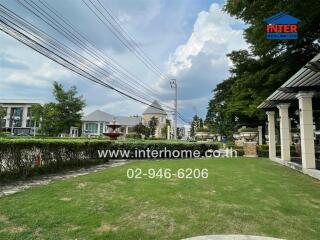 Spacious green yard in a residential area with a fountain and surrounding houses