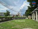 Spacious green yard in a residential area with a fountain and surrounding houses