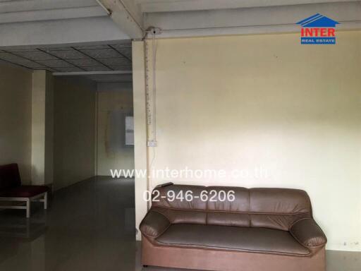 Living room with brown sofa and visible hallway