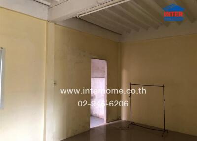 Basic unfurnished room with a doorway, fluorescent lighting, and a clothing rack