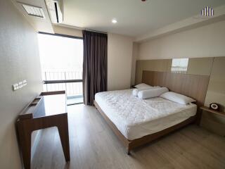 Spacious bedroom with a large bed, desk, and balcony access