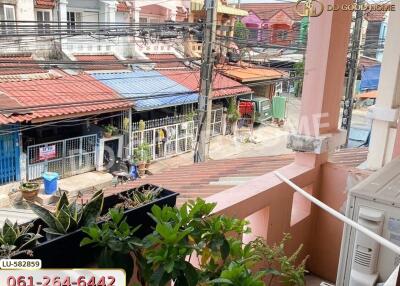 View from the balcony overlooking neighborhood houses with potted plants and an air conditioning unit seen on the side