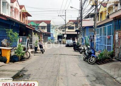 Street view of a residential area with houses, motorbikes, and cars parked by the roadside