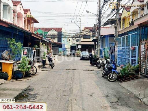 Street view of a residential area with houses, motorbikes, and cars parked by the roadside