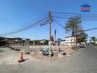 Empty plot of land on a street corner with few structures and commercial signage