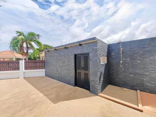 Modern outdoor shower area with black stone wall