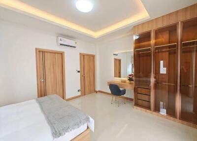 Spacious bedroom with modern design, large wardrobe, and vanity area