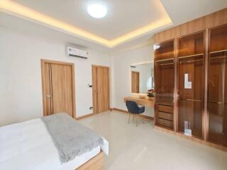 Spacious bedroom with modern design, large wardrobe, and vanity area