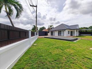 Exterior view of a house with a spacious lawn and a swimming pool