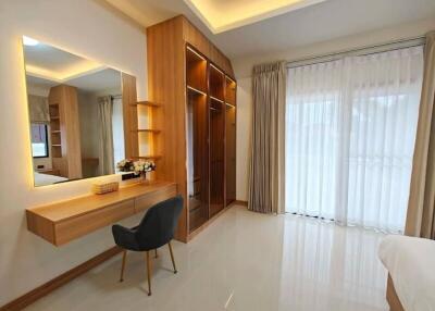 Modern bedroom with vanity desk, chair, closets, and large window