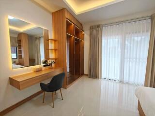 Modern bedroom with vanity desk, chair, closets, and large window