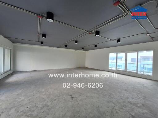 spacious empty room with large windows and ceiling lights