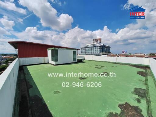 Rooftop with green flooring and a small white structure under a clear sky