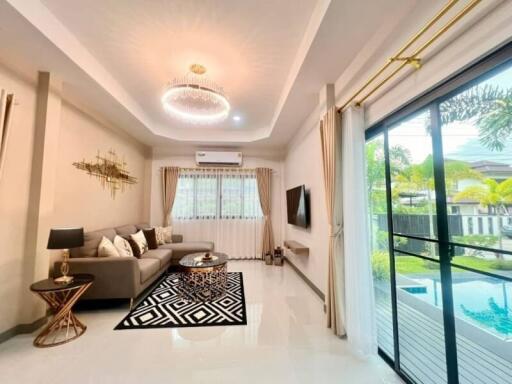 Spacious and modern living room with sofa, coffee table, TV, and large window with view