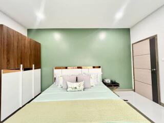 Spacious modern bedroom with green accent wall and stylish furniture