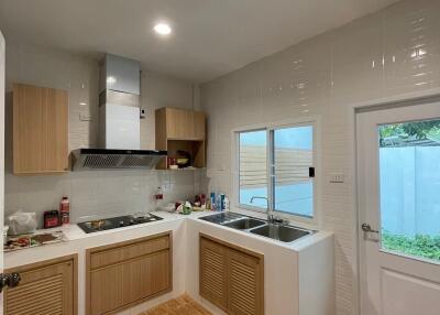 Modern kitchen with wooden cabinets, stovetop, and outdoor access