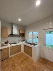 Modern kitchen with wooden cabinets, stovetop, and outdoor access