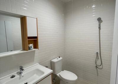 Modern bathroom with white tiles, sink, toilet, and shower