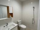 Modern bathroom with white tiles, sink, toilet, and shower