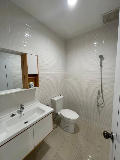 Modern bathroom with white tiles, sink, toilet, and shower