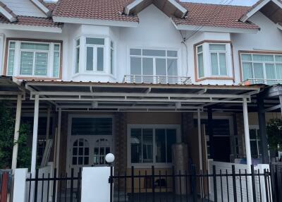 Exterior view of a townhouse with a covered parking area and front fence