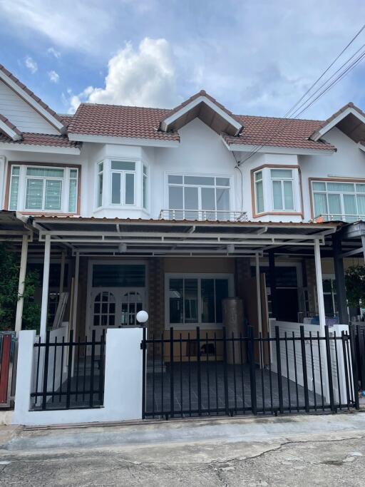 Exterior view of a townhouse with a covered parking area and front fence