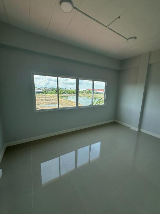 Empty bedroom with large window and tiled floor